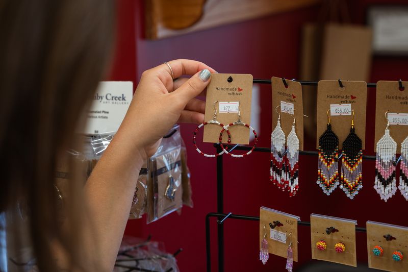 visitor holding Indigenous made earrings sold at Ruby Creek Art Gallery