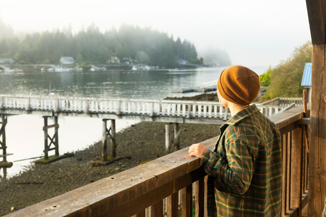 Upnit Lodge- Huuayaht First Nation. person looking out over balcony at the pier in the marina