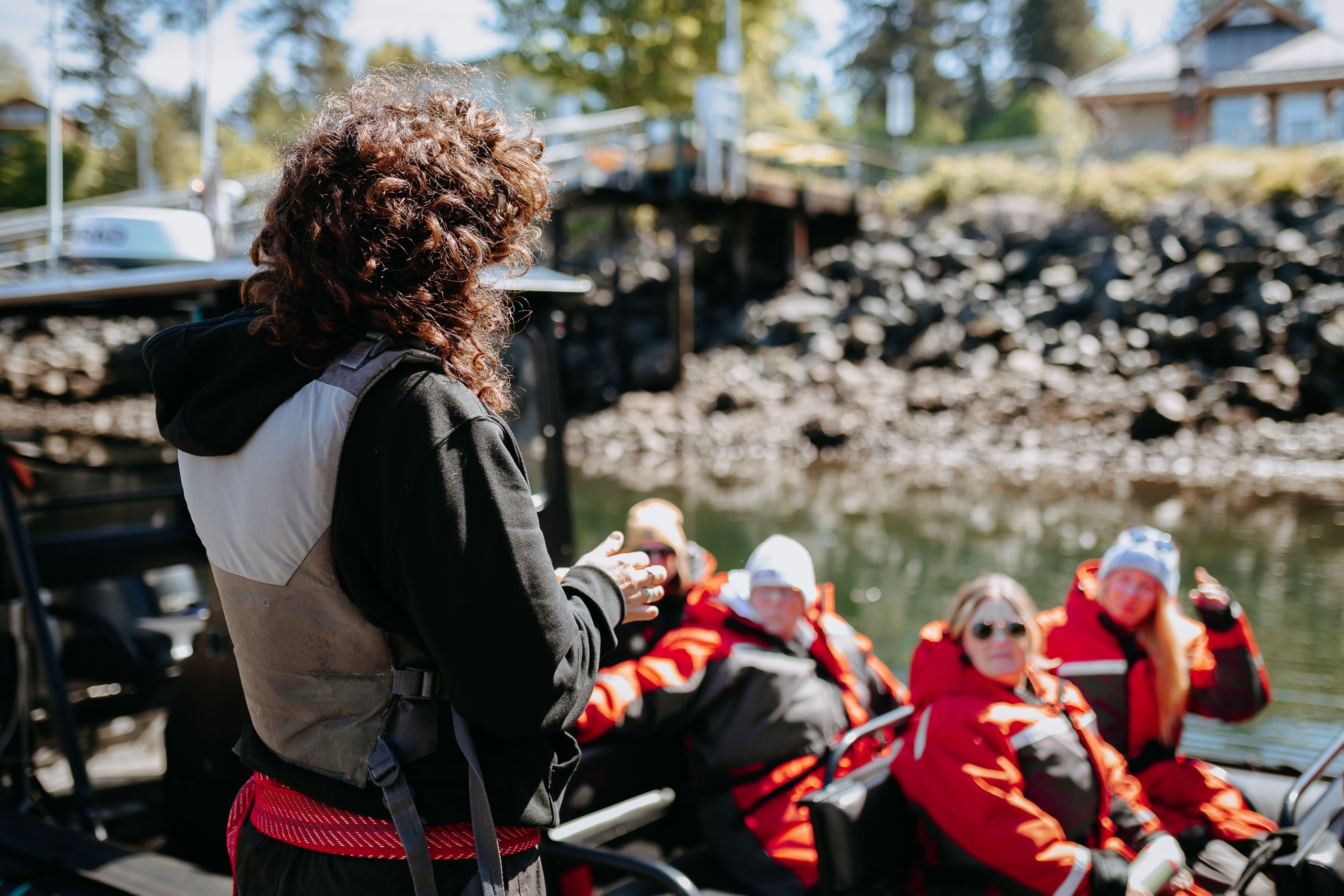 guide preparing guests for adventure with Wild Waterways Adventures- guests seated in boat, with gear and life vests on on a clear, sunny day at the marina.