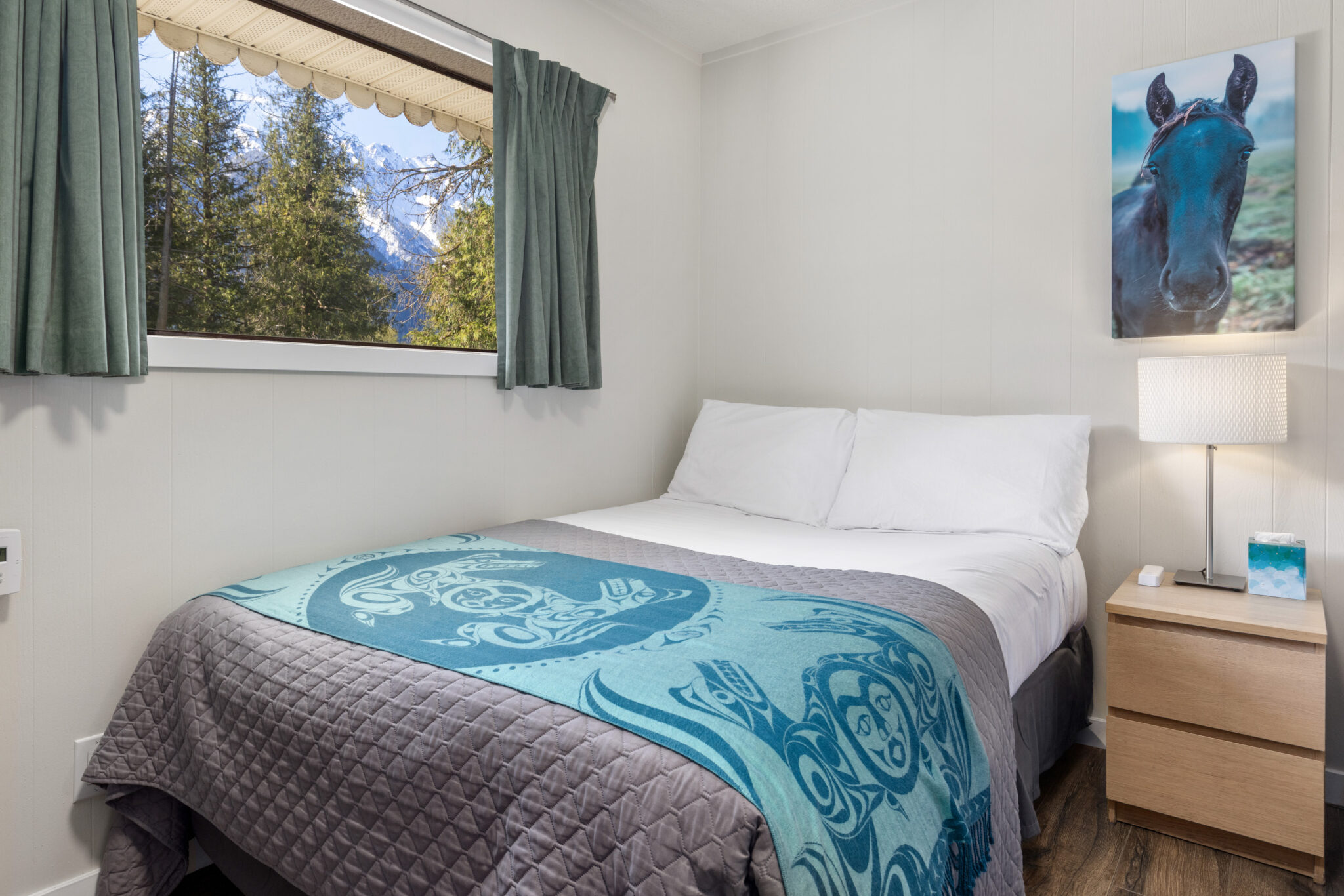 double room with a double bed, with an Indigenous designed throw blanket and blue accents in the room