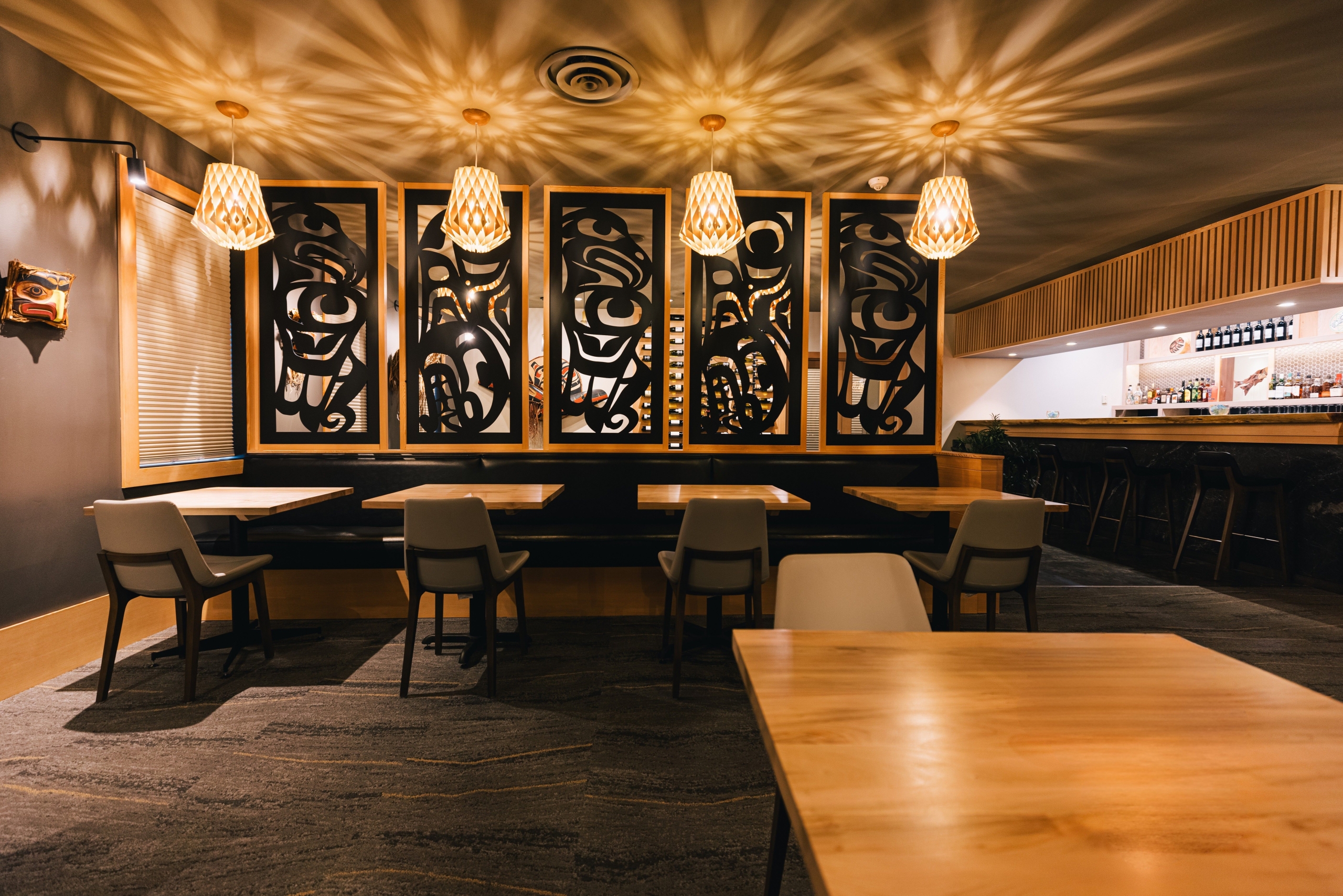 indoor dining room with low lighting, indigenous art and bar at Ha'Me' Restaurant at Kwa'lilas Hotel