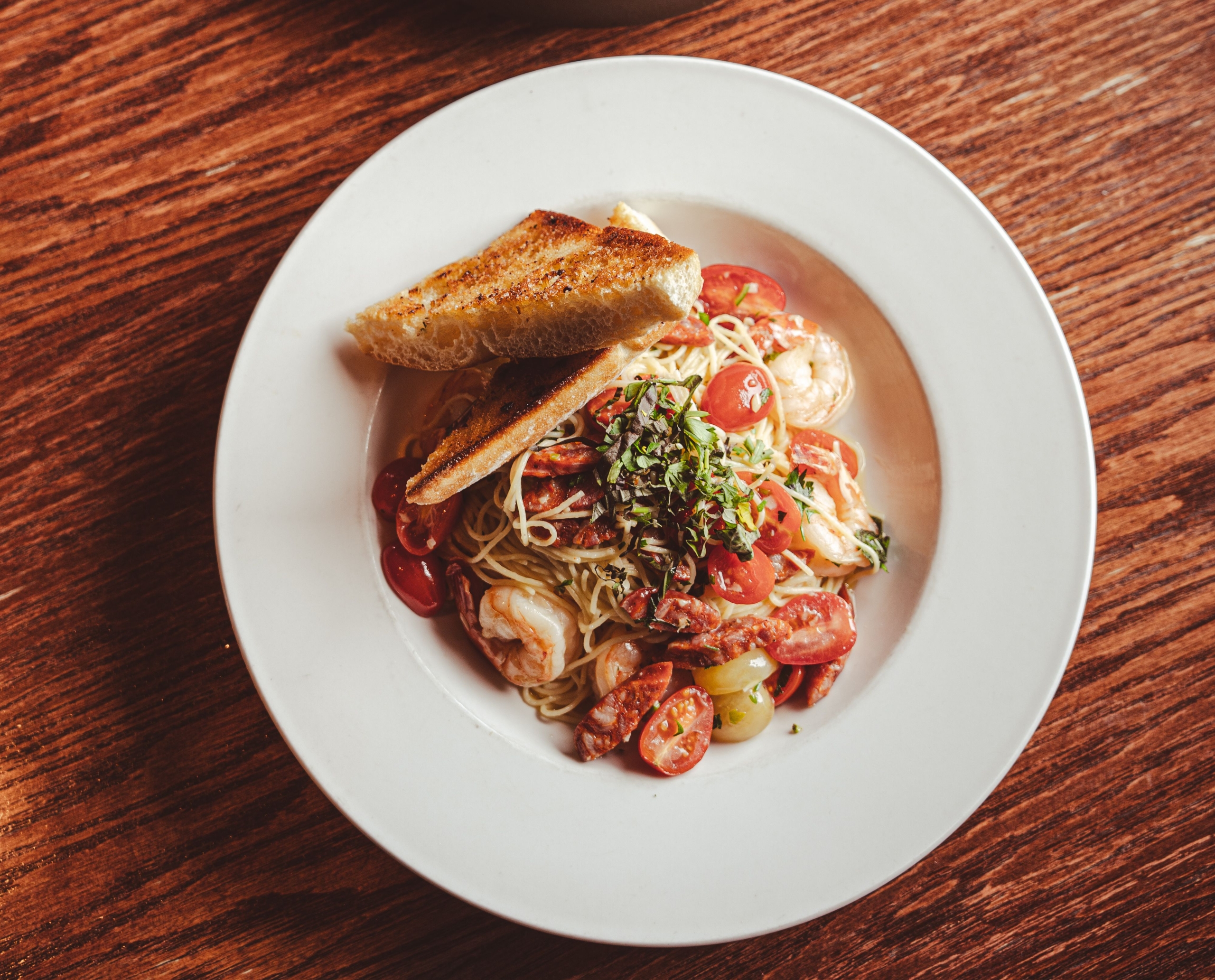 Fresh seafood pasta dish with tomatoes, shrimp, garlic bread and herbs served at Nax'id' Pub in Port Hardy, BC.