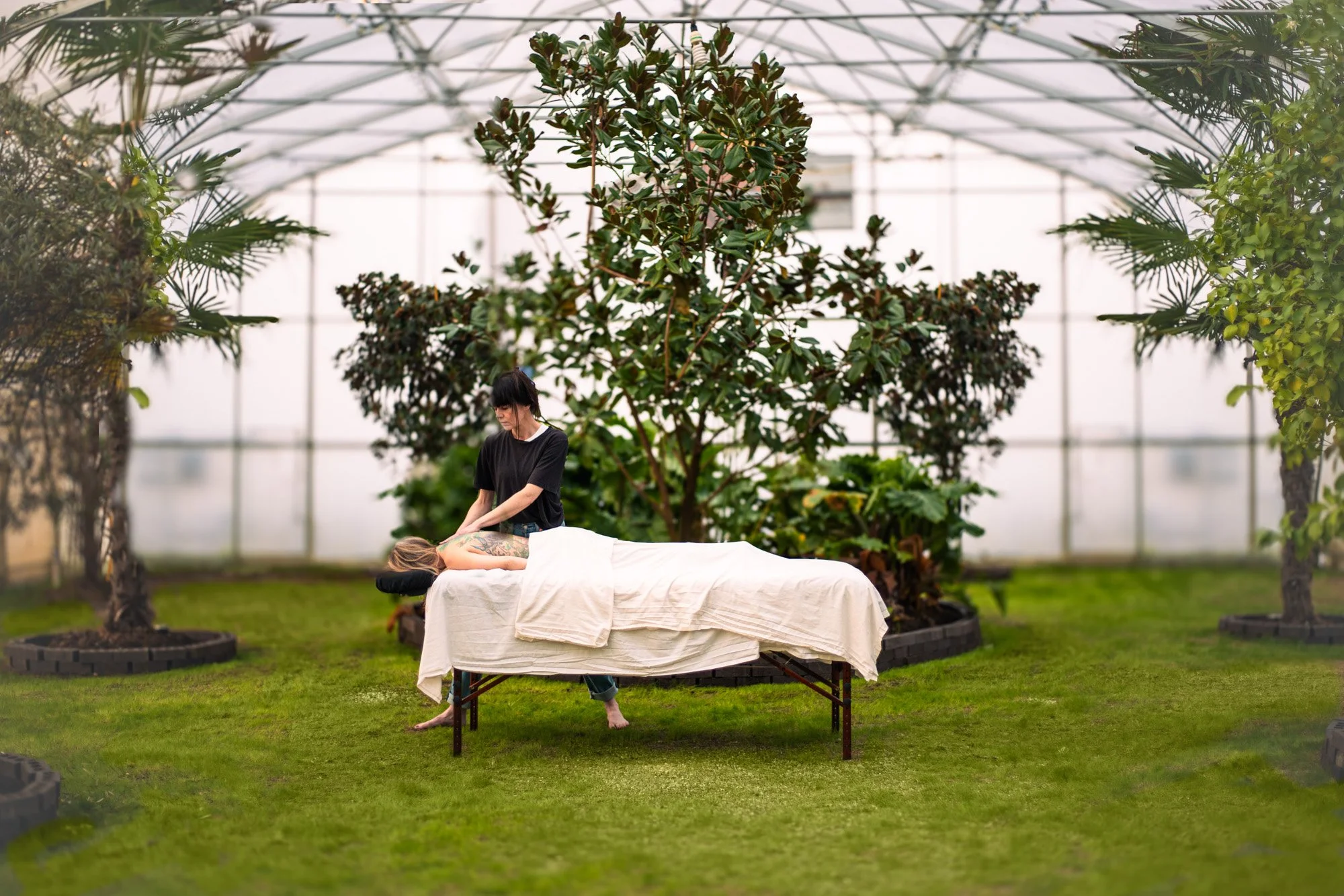 green grass in greenhouse at Kinnikinnick Landing Wellness Retreat with a woman getting a massage surrounded by lush trees