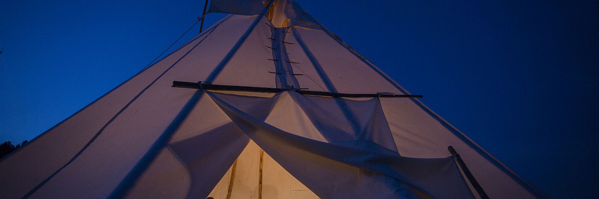 A view of the inside of a Teepee from the opening, revealing people inside.