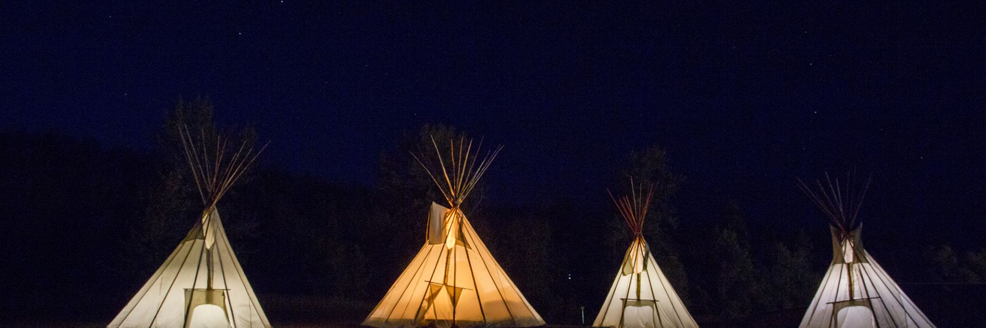 A nighttime view of four teepees