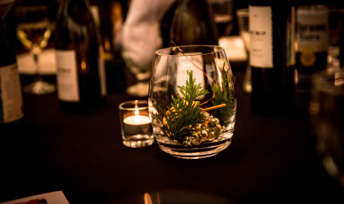 An indigenous dessert in a glass with spruce leaves and a tea light lit on the table.