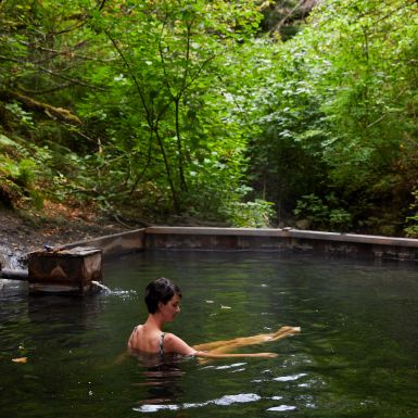 A woman stretches her legs at the Hldu Isgwit Hot Springs