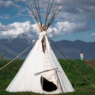 A white teepee stands in the foreground with the Kootenay Rockies in the background