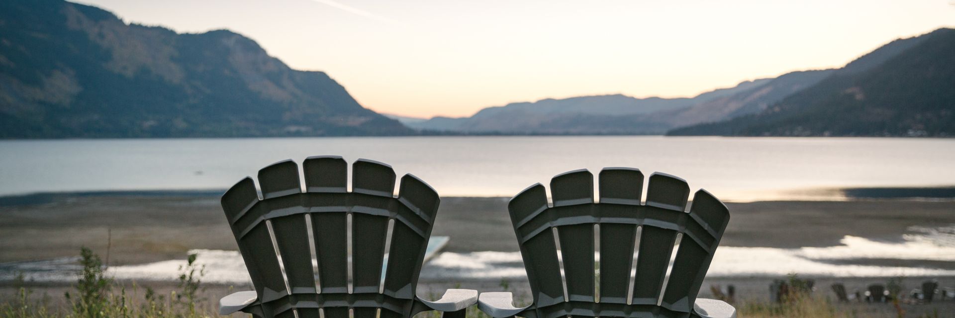 two beach chairs sit facing a body of water with mountains in the background