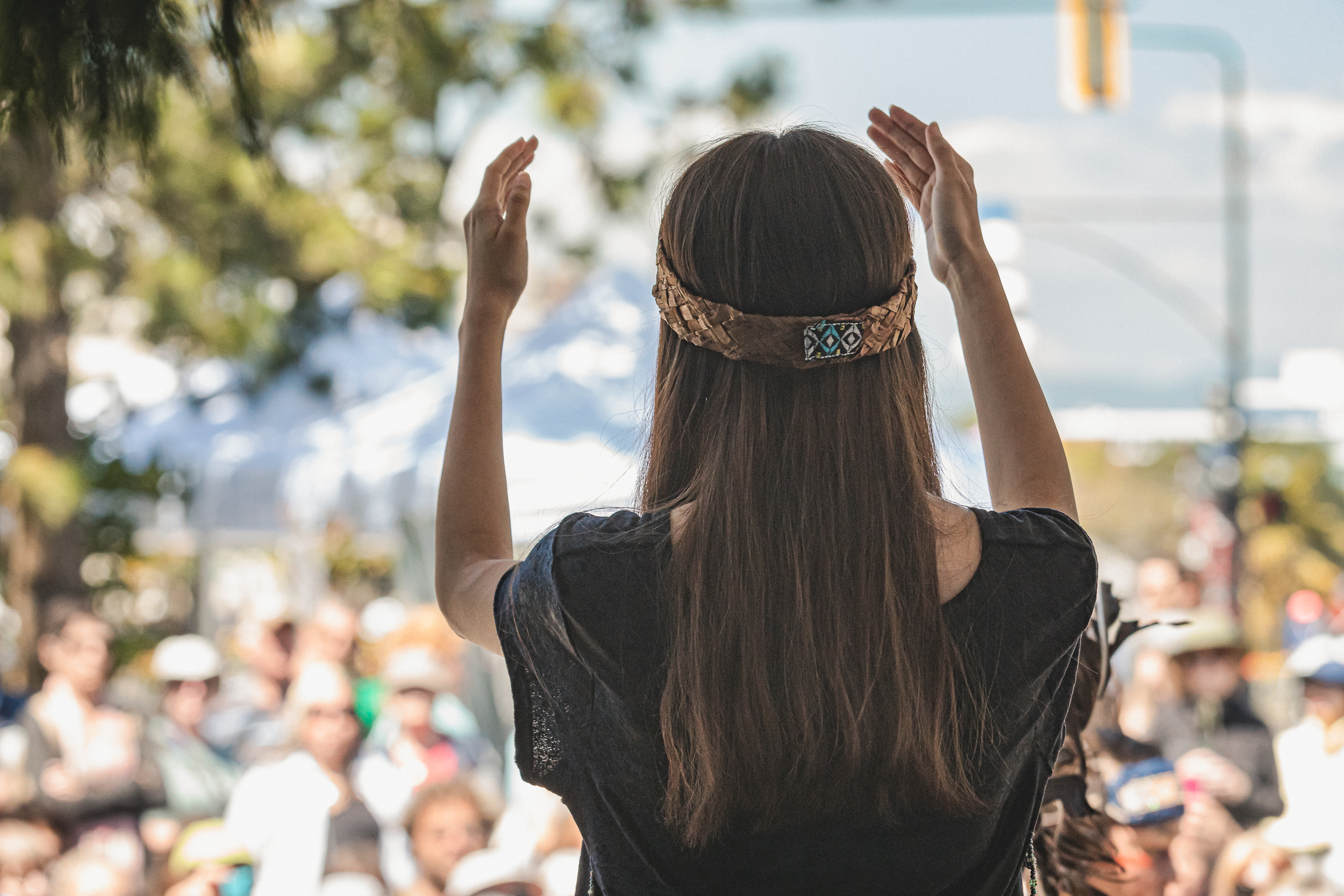 A woman raises her hands as she addresses a crowd.