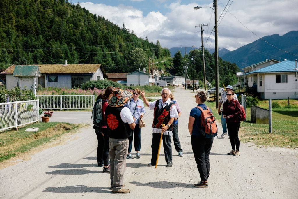 A man stands on a dirt road and leads a group on a Gingolx Elder Tour