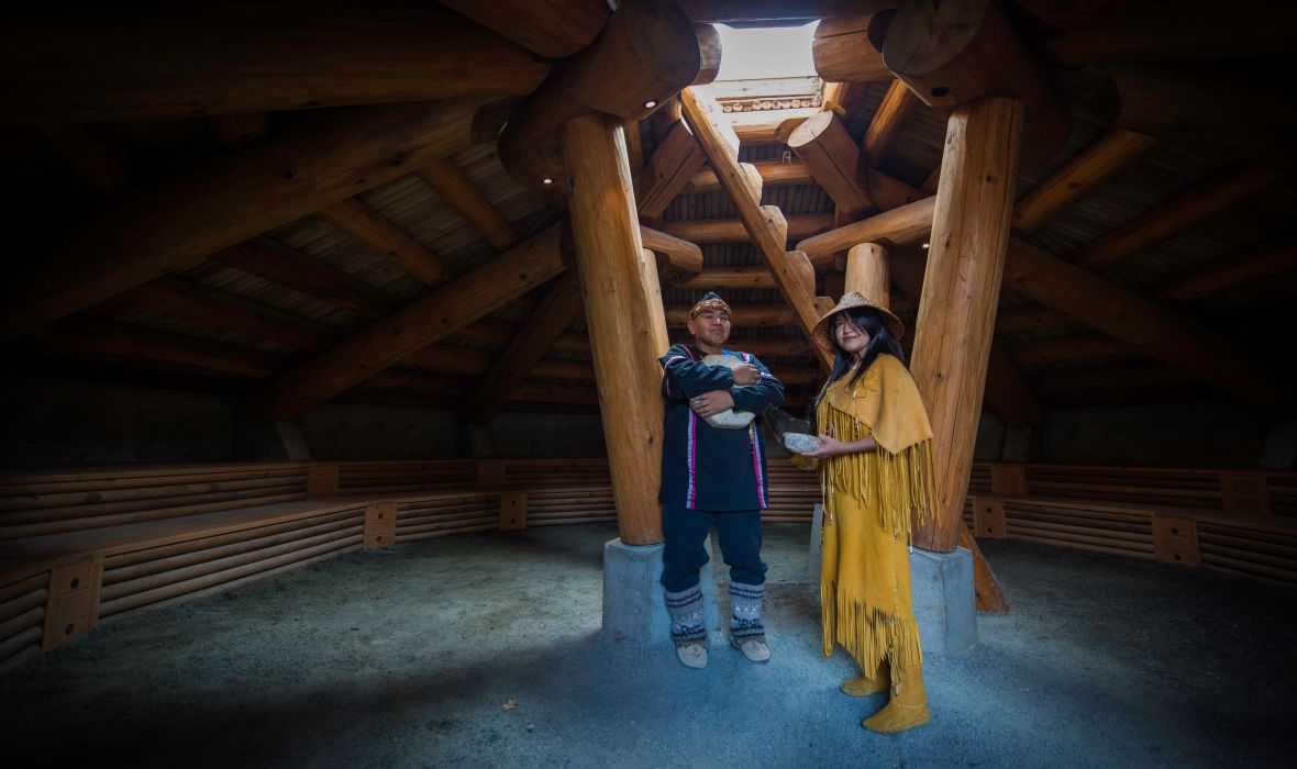 Two people in traditional clothing inside a hut