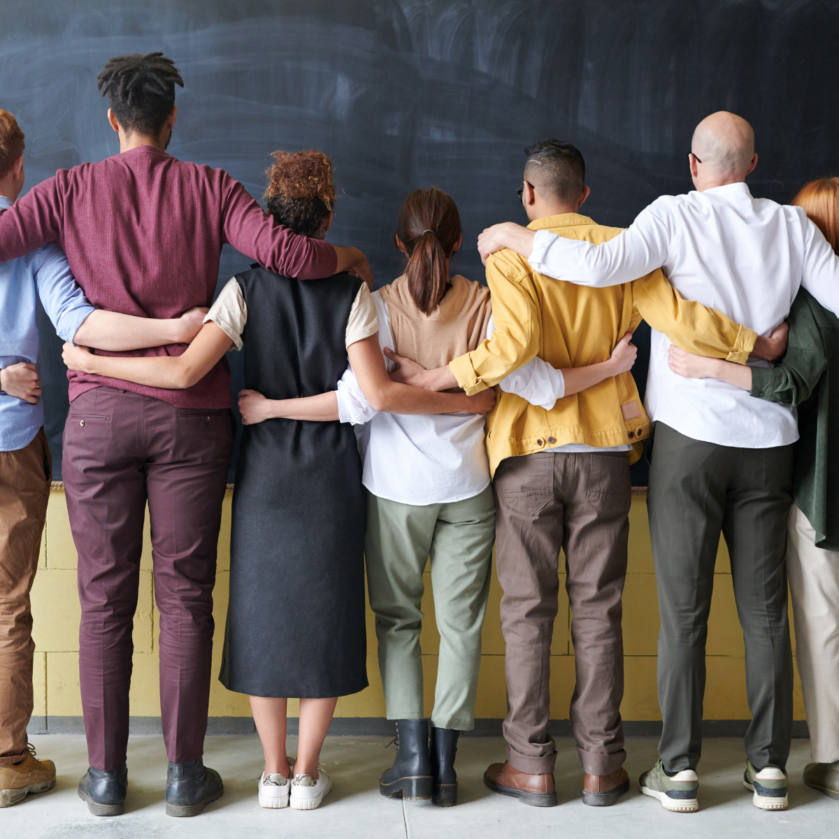 Seven people standing looking at a chalk board demonstrating Equity Diversity Inclusion