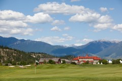 Green d'un terrain de golf en face des bâtiments du St. Eugene Golf Resort Casino avec les montagnes en arrière-plan.