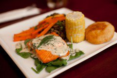Une présentation appétissante de la gastronomie moderne des Premières Nations, comprenant saumon et bannique sur une assiette blanche carrée.